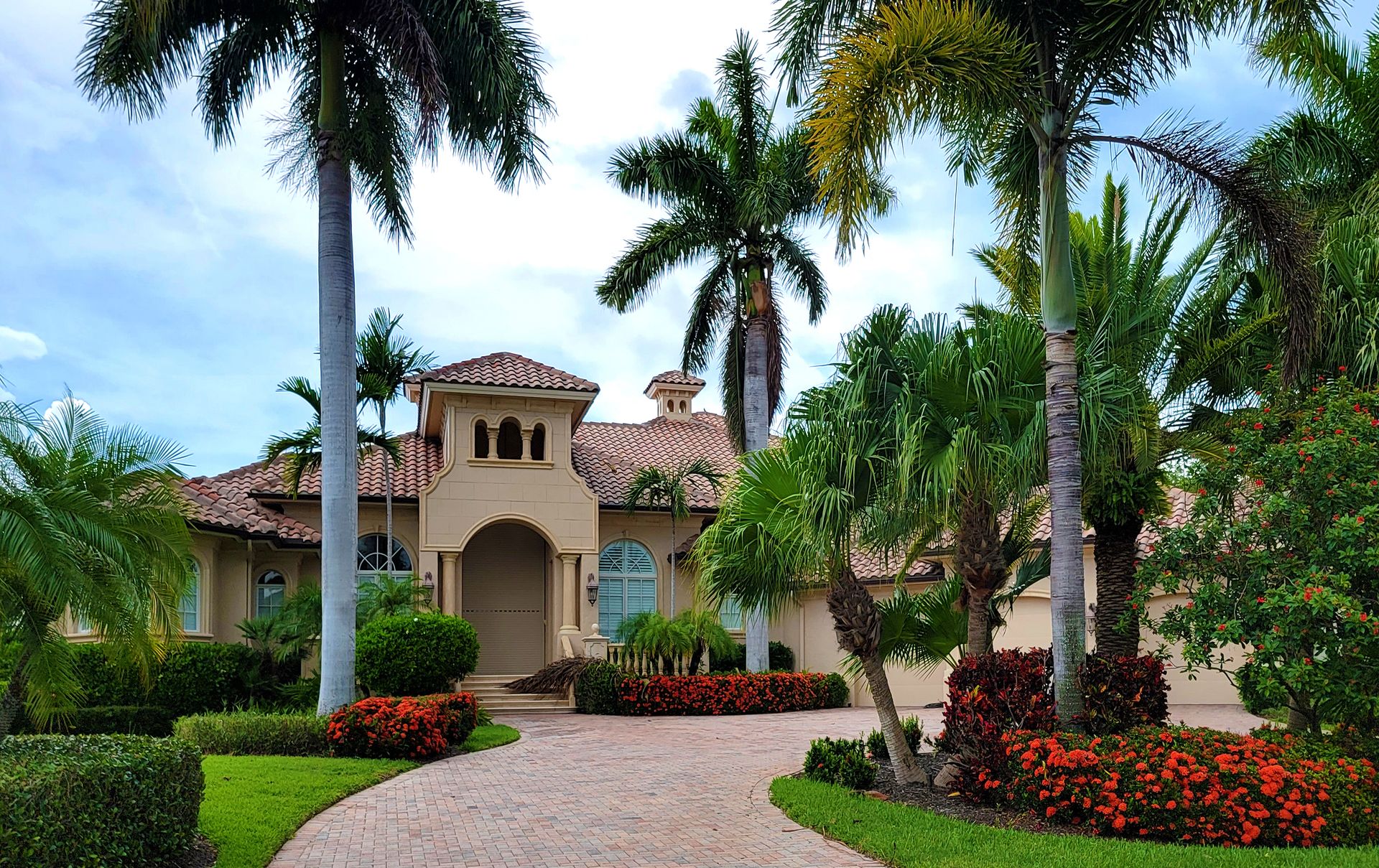 Florida landscape design with palms, paver driveway and colorful beds